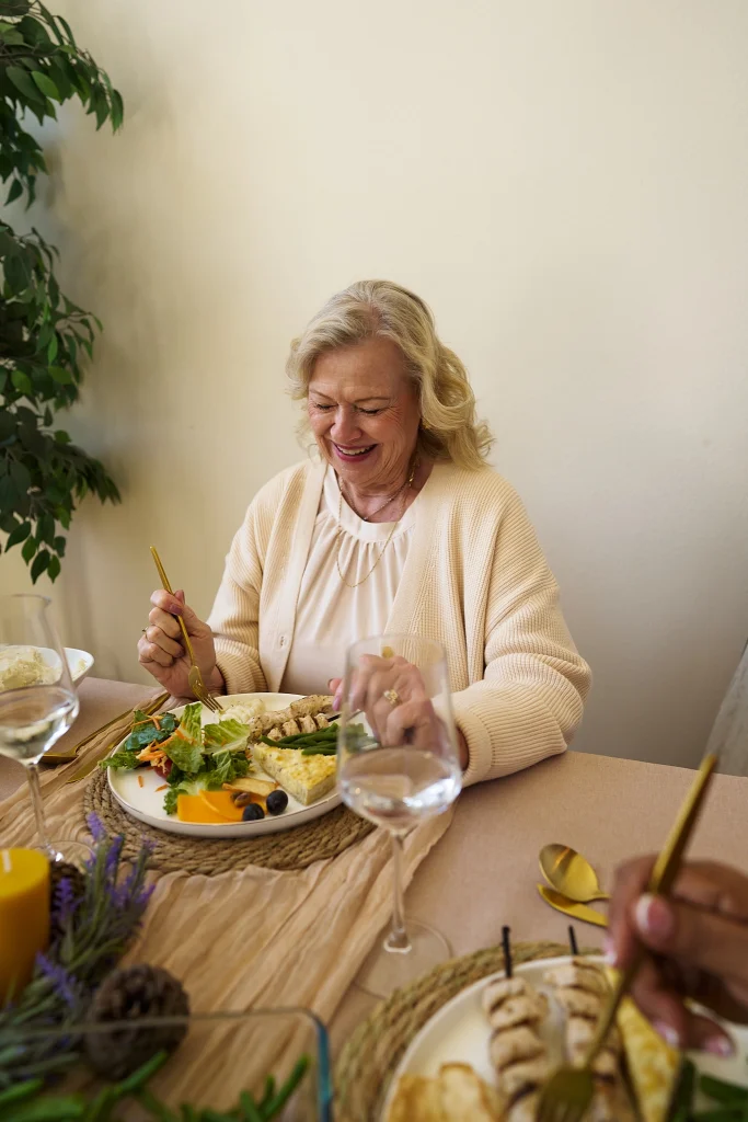 older woman at dinner table eating healthy.