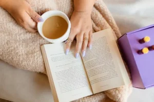 woman's hands holding coffee cup and book, reading about what is functional medicine.