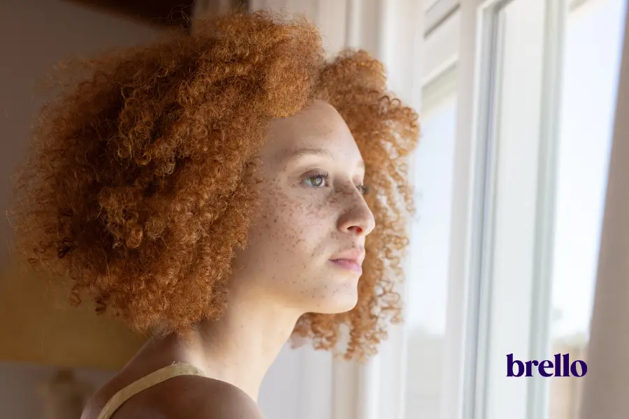Woman opening her curtains to morning light, starting a calm daily routine for what causes inflammation article.