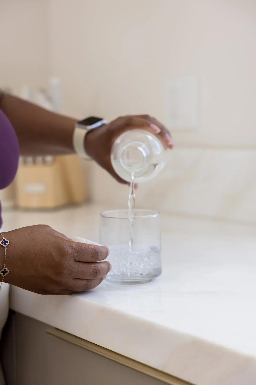 Woman setting out her daily supplement routine with the best electrolytes for hydration on a kitchen counter