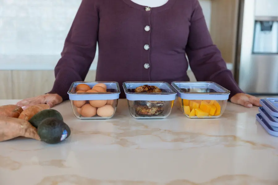 Glass containers of eggs and prepared food lined up on a kitchen counter